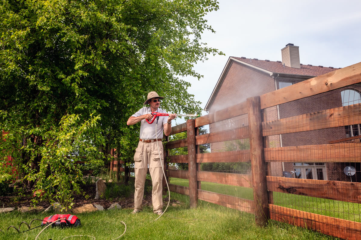 Picture of a guy power washing his fence.  Prevention.